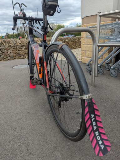 Well used A well used bike with repaired mudguards, insulation tape and faded stickers leaning against a bike hoop.