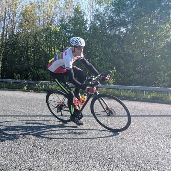 A cyclist cornering hard on a spring morning; they've got tights and long sleeves on, their bike has mudguards.