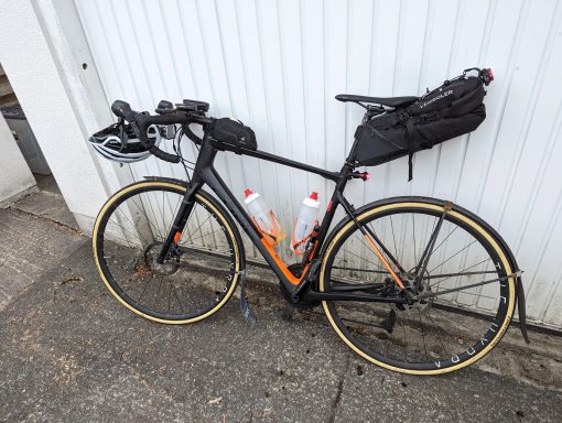 Commute+ A bike leaning against a garage door with a bike packing bag mounted on the seat.