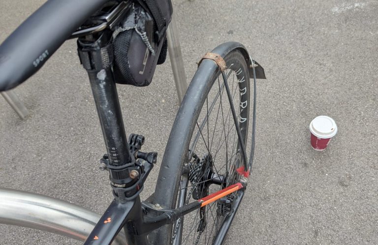 Perfectly imperfect. Looking down at an old bike with a patched up saddle bag, paint worn off the seat tube, faded paint and repaired mudguards.