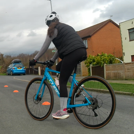 A cyclist riding around some cones on a quiet cul-de-sac
